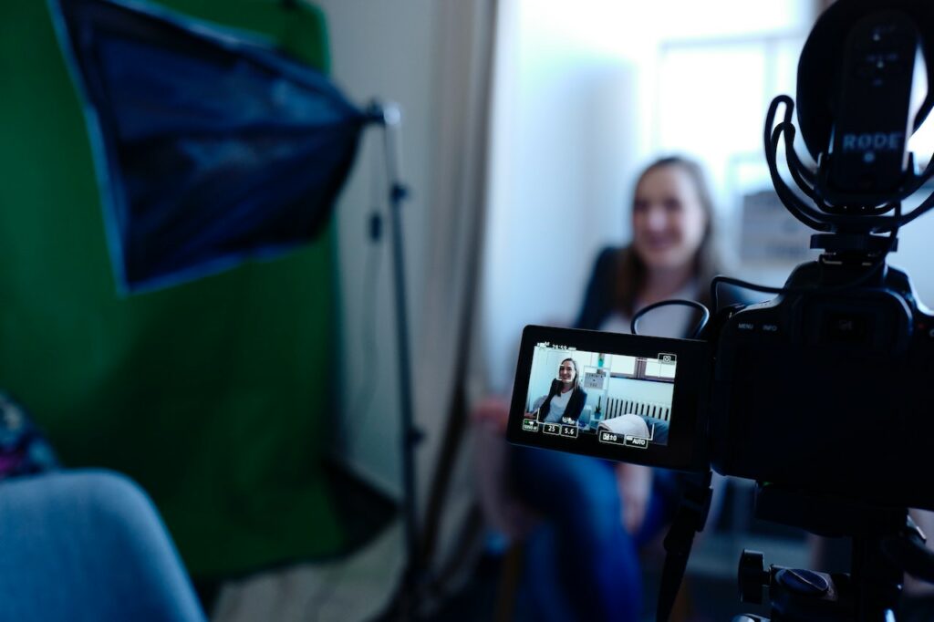 A person in front of a camera, with the camera equipment visible in the photo frame.