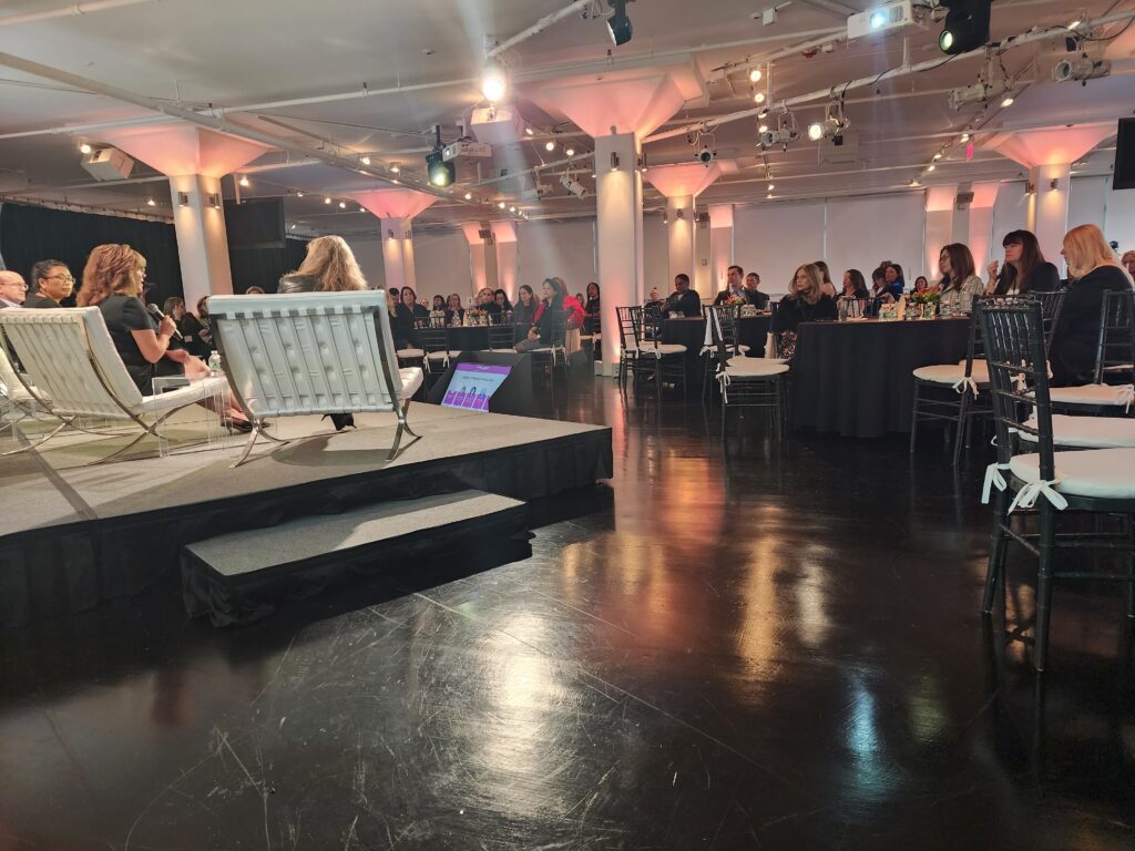 A crowded room with people seated around a dais.